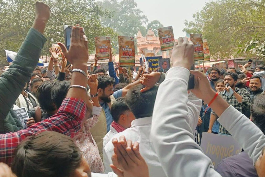 A crowd of students raise their fists and hold up placards on the Banaras Hindu University campus