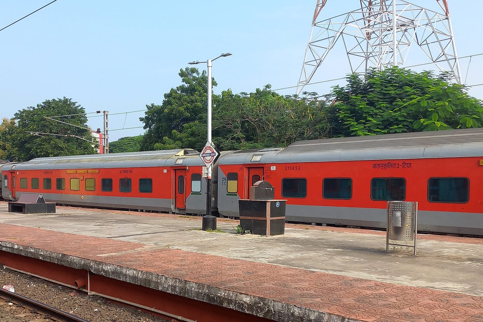 An empty platform at Kakinada Town railway station with a red-and-grey passenger train alongside