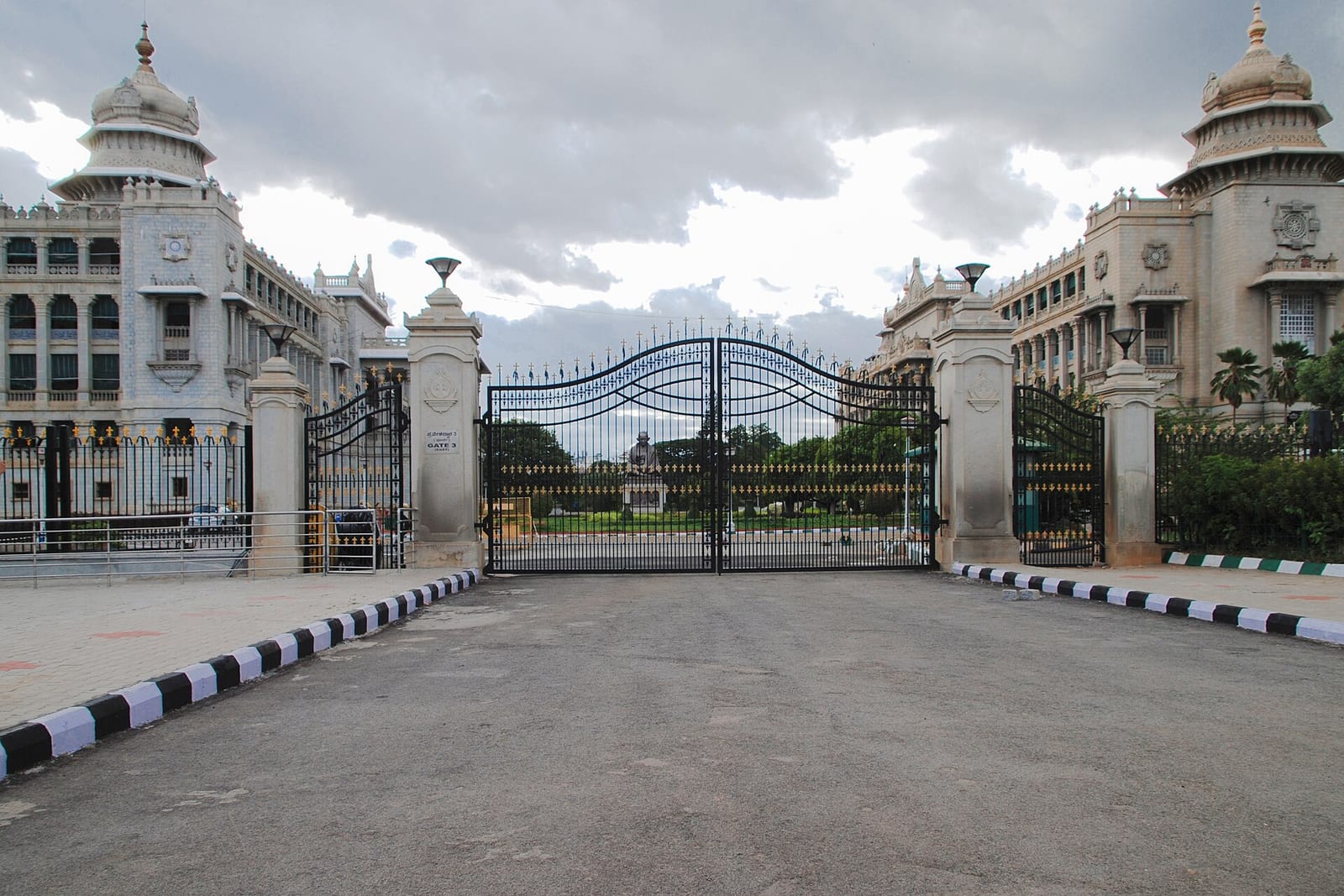 Closed iron gates at the east entrance of Vidhana Soudha, Karnataka's legislature building in Bengaluru, under a cloudy sky