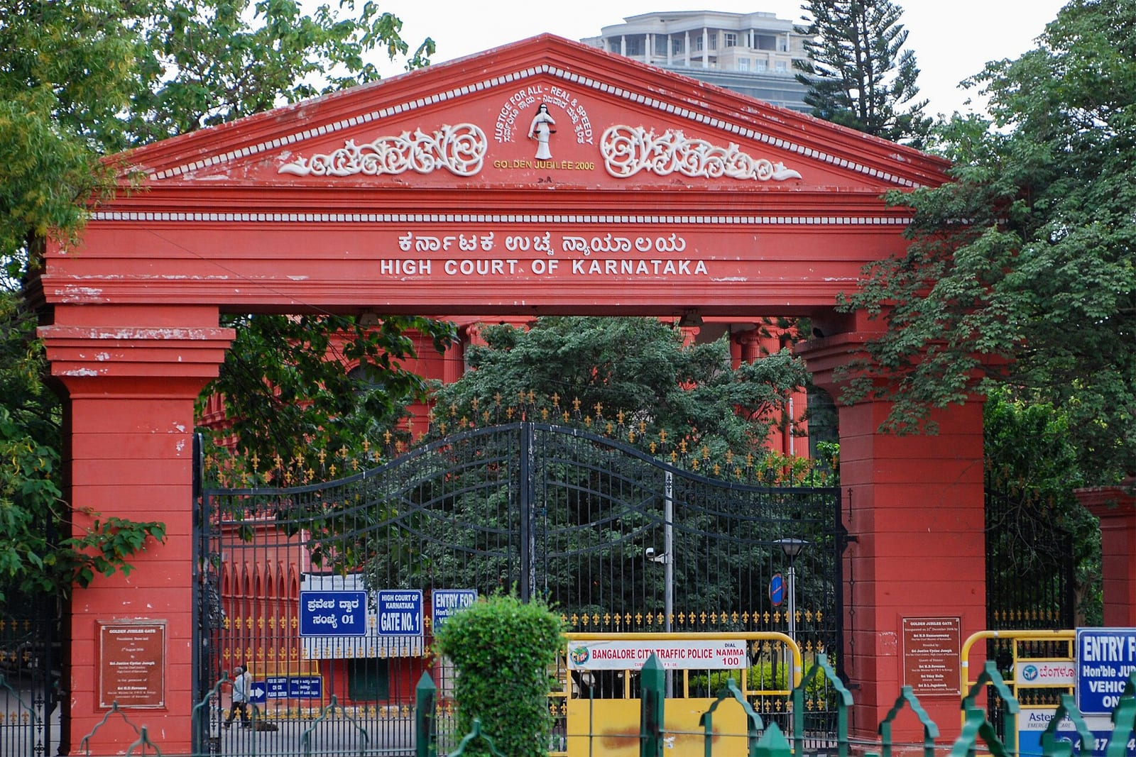 The red gateway of the High Court of Karnataka in Bengaluru, its name in Kannada and English above closed iron gates
