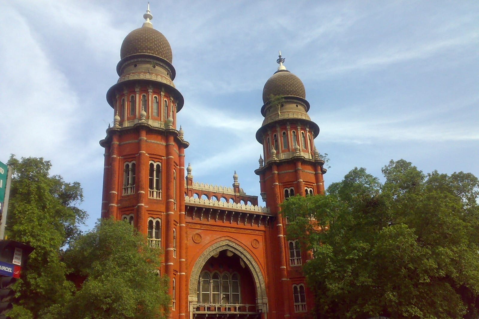 The domed red-brick towers of the Madras High Court in Chennai, framed by trees