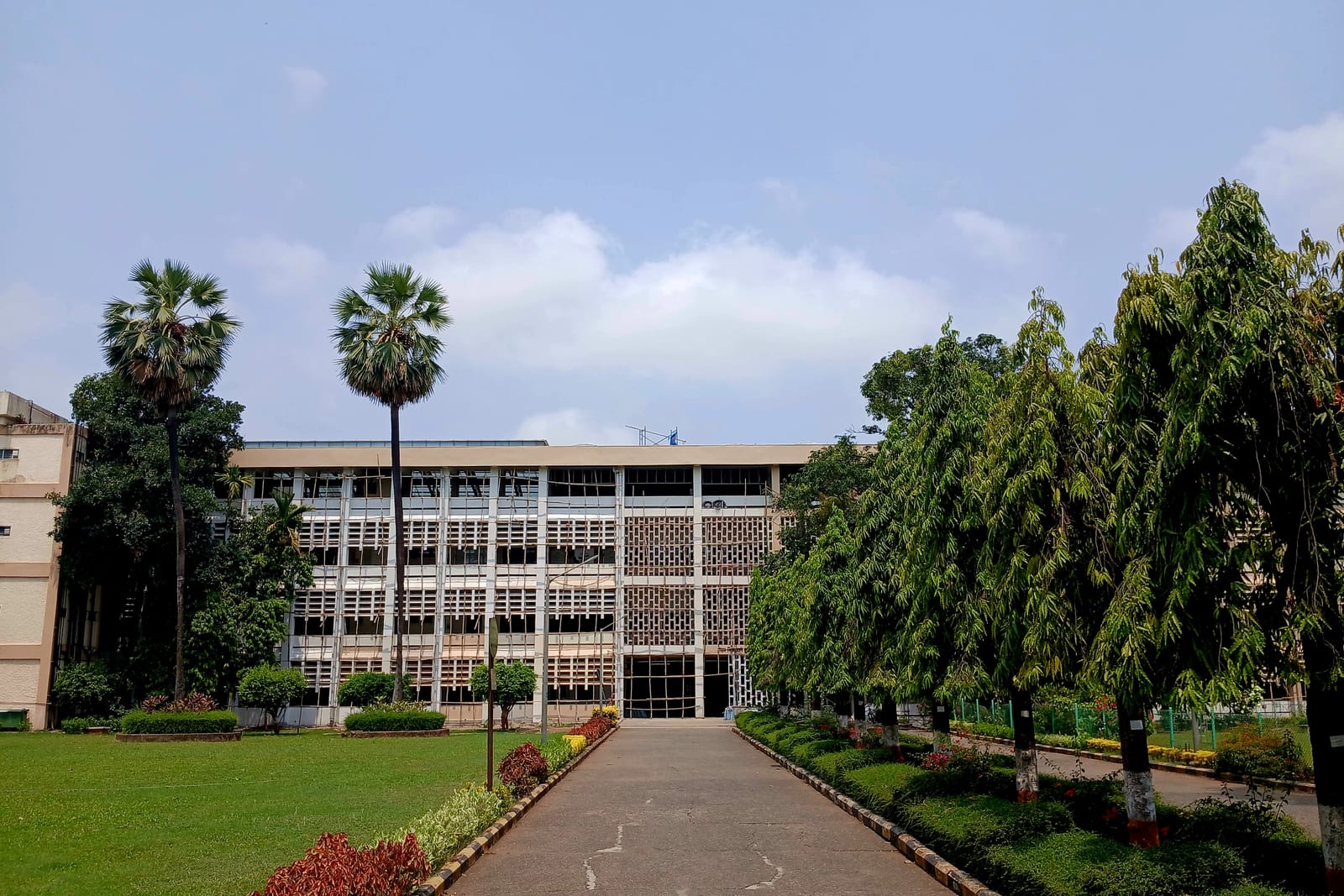 IIT Bombay's main building, a long white modernist block behind a tree-lined path and lawn, Powai, Mumbai