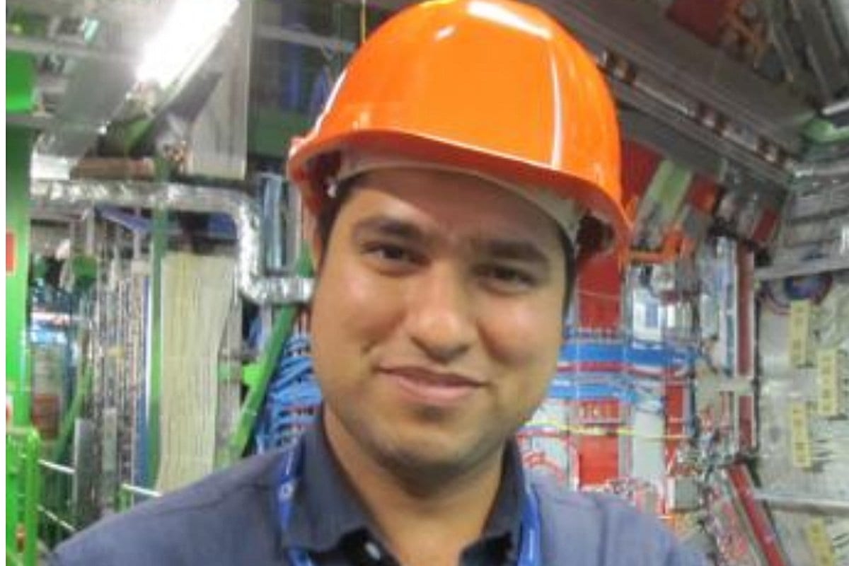Ashok Kumar, smiling, in an orange hard hat inside a physics laboratory